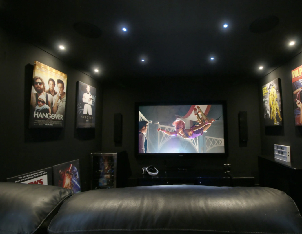 Black cinema room with leather seating and movie posters on walls